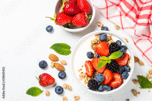 Greek yogurt granola with fresh berries on white table.