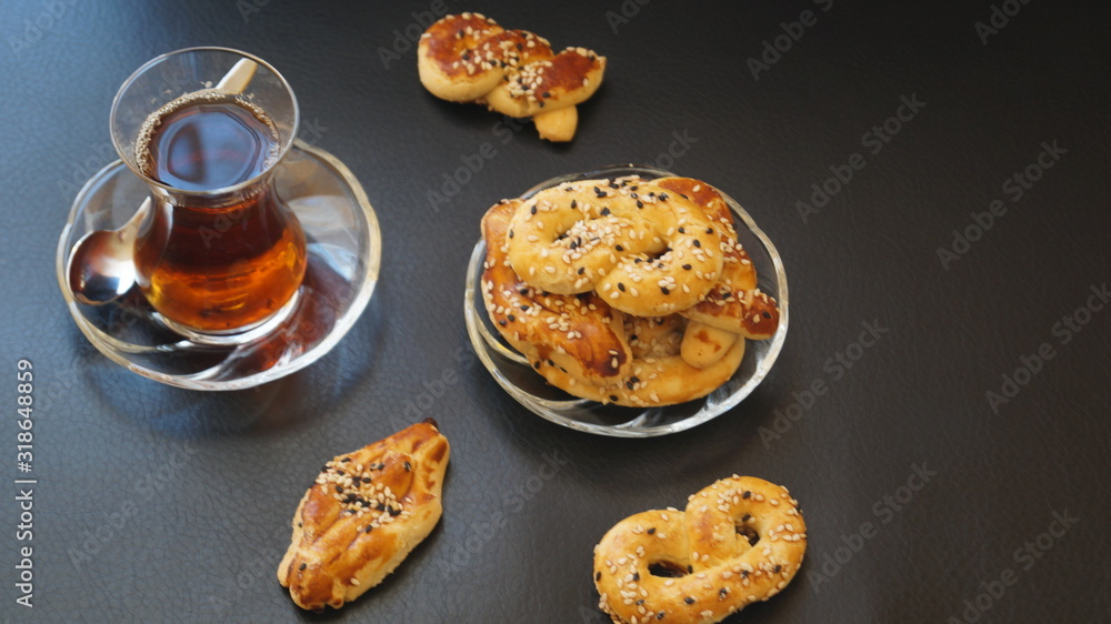 traditional turkish cookies - kurabye and tea in a glass cup on a black table traditional turkish cookies - kurabye and tea in a glass cup on a black table