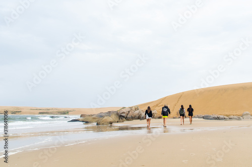 Woman wlaking in the beach near fron a dunes - Barra de Valizas, Uruguay photo
