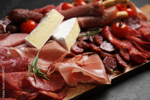 Tasty ham with other delicacies served on black table, closeup