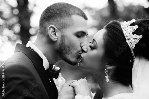 Beautiful couple on their wedding day. Portrait of groom and bride. Romantic atmophere on the wedding. Married couple kissing. Bride and groom in love. Black and white photo