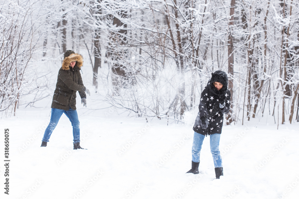 Fun, season and leisure concept - love couple plays winter wood on snow