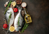 Fresh dorado fish with spices and ingredients tomato, razmorin, sunflower oil, lemon for cooking on a stone background with copy space for your text