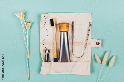 Zero waste self-care products for travel. Bamboo toothbrush, toothpaste, , tongue cleaning and flax. Flat lay style.