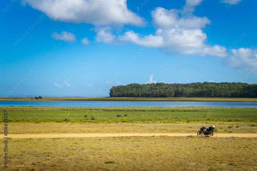 A small motorcycle in front of a big lake - Laguna de Rocha, Uruguay