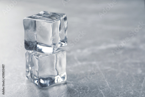 Crystal clear ice cubes on grey table. Space for text