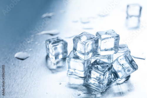 Crystal clear ice cubes with water drops on metal surface