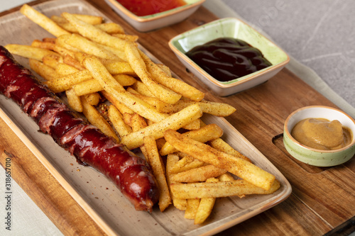 Fried sausage with french fries served on plate
