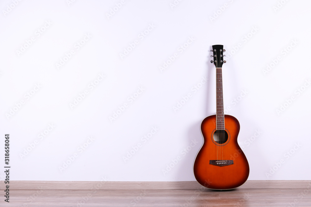 Fototapeta premium Folk style parlor acoustic guitar over white wall background with a lot of copy space for text. Studio shot of travel size musical instrument. Close up.