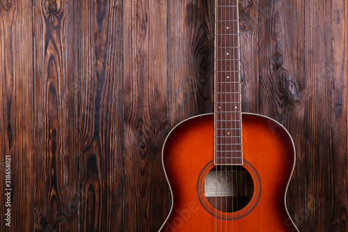 Top view of folk style parlor acoustic guitar over wood textured table background with a lot of copy space for text. Close up shot of travel size musical instrument.