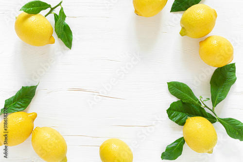 Fresh lemons with leaves on white wooden background,  summer lemonade ingredient, vitamin c concept, top view.