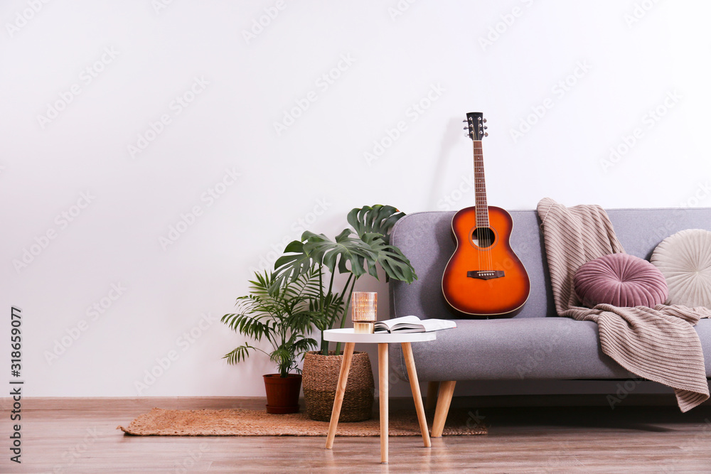 Minimalistic interior design concept. Acoustic guitar on grey textile sofa  in spacious room of loft style apartment with wood textured laminated  flooring. Background, copy space, close up. Stock Photo | Adobe Stock