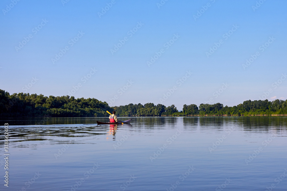 Rear view of man paddling the wooden kayak in the lake or river