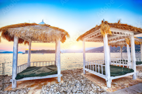 Fototapeta Naklejka Na Ścianę i Meble -  Thatched canopies and awnings on the beach Copacabana at sunset in Dubrovnik