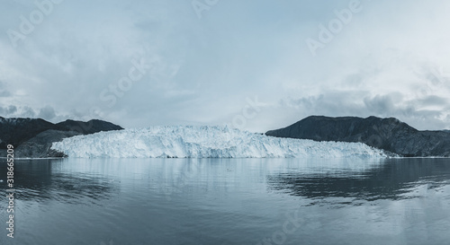 Close Up shot of huge Glacier wall. Large chunks of ice breaking off. Moody and overcast weather. Eqip Sermia Glacier called Eqi Glacier. Greenlandic ice cap melting because of global warming.