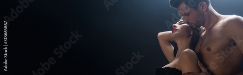 Panoramic shot of shirtless man embracing sexy woman isolated on black