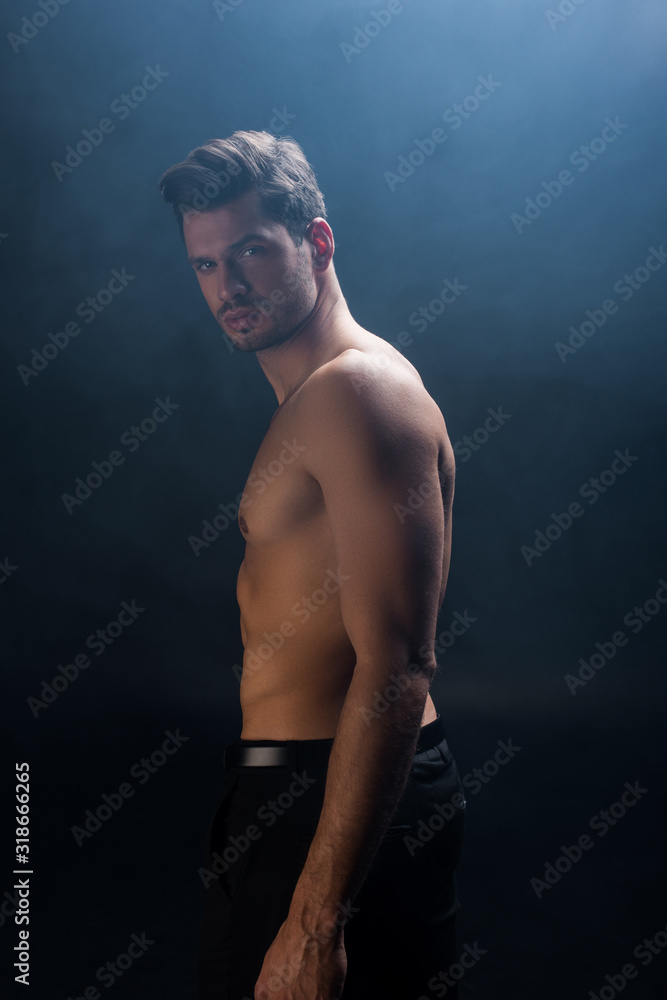 Side view of shirtless man looking at camera on black background with smoke  Stock Photo | Adobe Stock