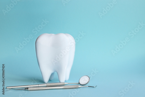 White tooth with dental instruments on a blue background in honor of the international day of the dentist on February 9