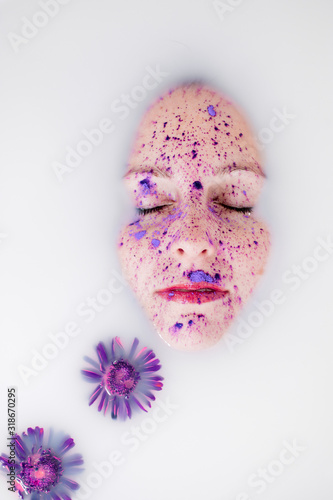 Fototapeta Naklejka Na Ścianę i Meble -  Portrait of a young woman in milk bath with purple flowers and powder 