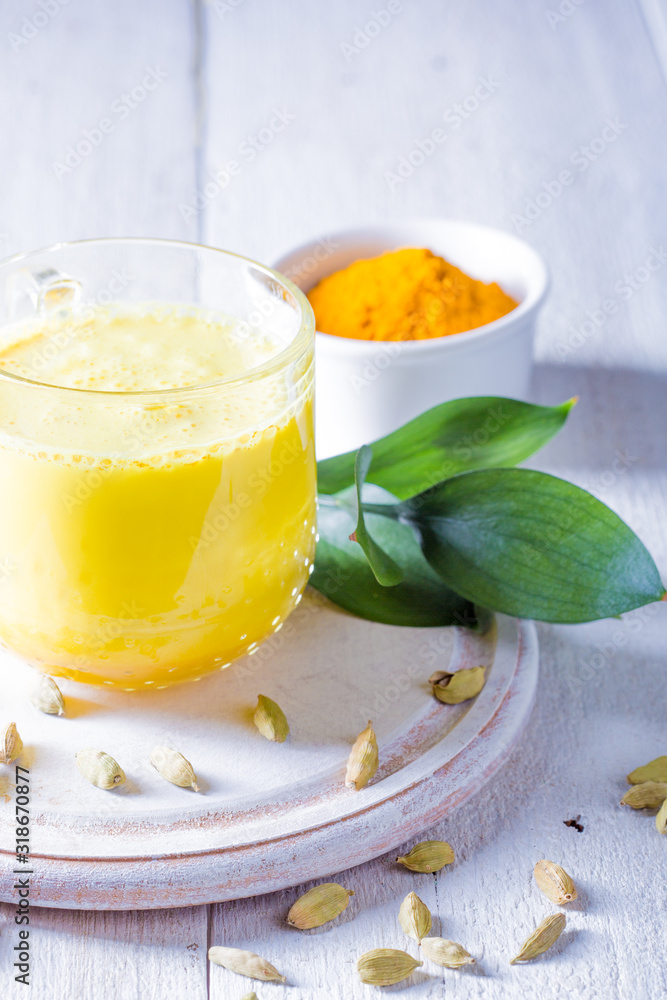 Cup with golden latte, turmeric and cardamom on white background Cup with golden latte, turmeric and cardamom on white background