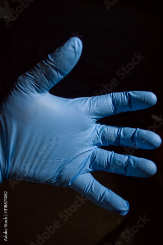 left hand in a rubber glove on a black background © alebor79