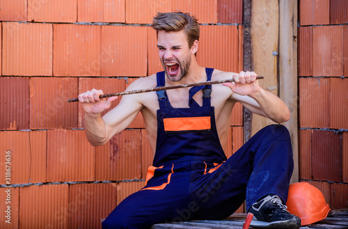 Strong enough. Man try to bend metal framework. Construction. Engineer with metal detail. Architect repairman. Worker man builder in work clothes. Feeling powerful and strong. Strong emotional guy photo