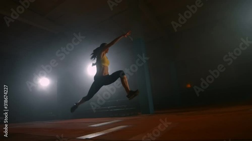 Women's track and field in slow motion, performing a long jump with a running start. Jump in the sand at competitions photo