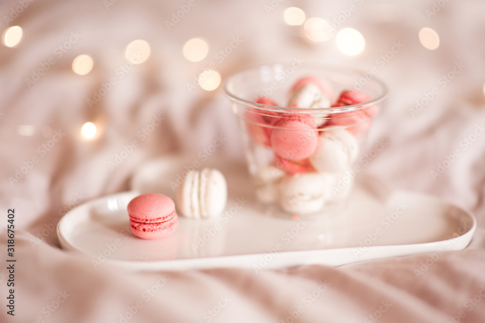 Tasty macaroon cookies on white plate in glass bottle over glowing lights closeup. Good morning. Tasty macaroon cookies on white plate in glass bottle over glowing lights closeup. Good morning.