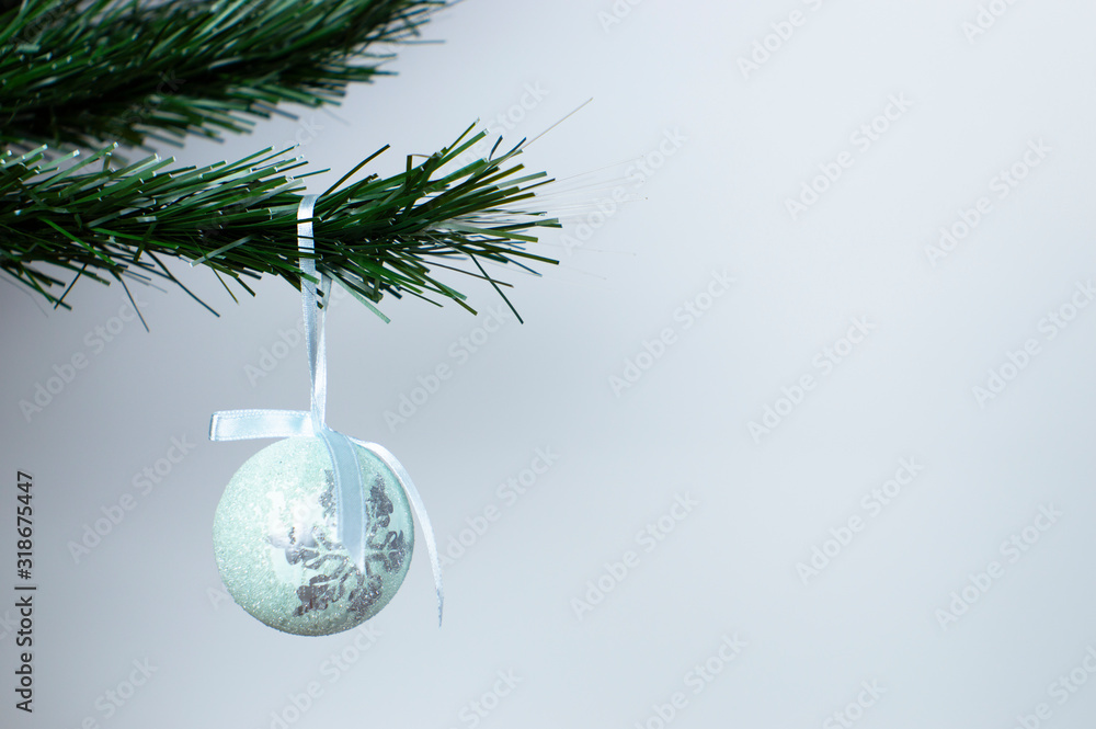 Christmas tree toy on a Christmas tree branch. White copy space. Blue toy ball. Merry Christmas and happy new year.