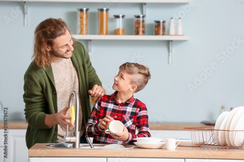 Father and son washing dishes in kitchen