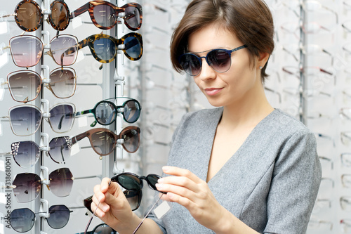 A young woman tries on sunglasses in an optics store