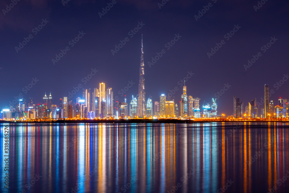 Beautiful view to Burj Khalifa and modern, luxury cityscape panorama from Dubai Creek and colorful reflection of lights in the water canal. Shot at blue hour. 