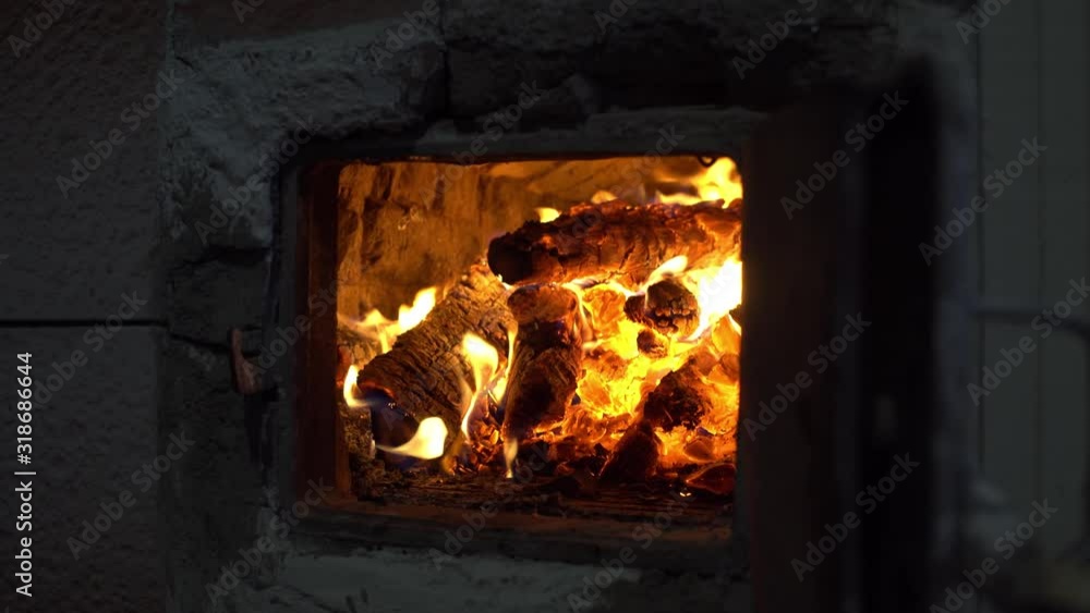 Burning wood and coals inside an old stove. Closeup view of a red hot glowing firewood. man closes the door of the oven. Burning wood and coals inside an old stove. Closeup view of a red hot glowing firewood. man closes the door of the oven.
