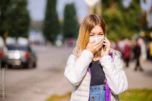 the girl is standing by the road in a protective medical mask. Dense smog in the streets of the city.