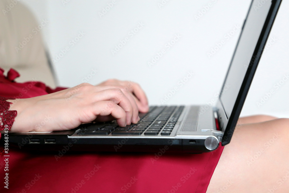 Girl using laptop in a bed, woman in seductive red nightie typing on the keyboard. Concept of working on a computer at home, online business, cozy atmosphere Girl using laptop in a bed, woman in seductive red nightie typing on the keyboard. Concept of working on a computer at home, online business, cozy atmosphere