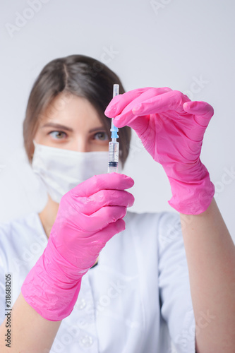medical in pink gloves holding syringe with injection. Checks at eye level
