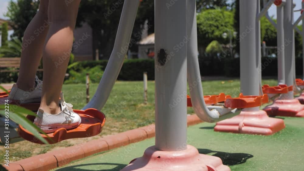 Girl child engaged in workout on street exercise equipment in the summer in the park. Girl child engaged in workout on street exercise equipment in the summer in the park.