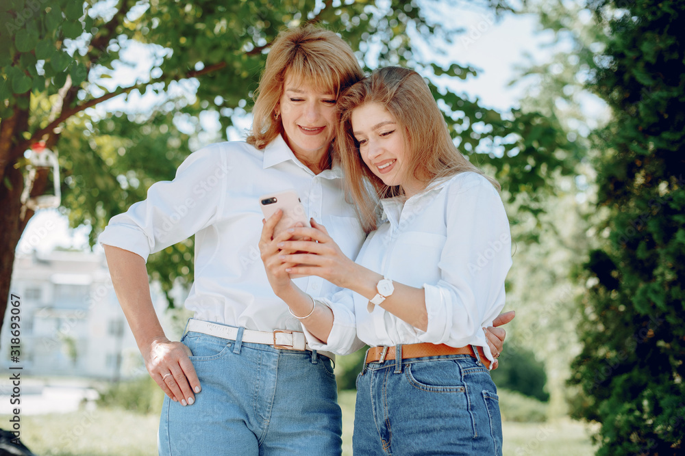 Elegant mother with young daughter. Family in a park. Women in a white shirts