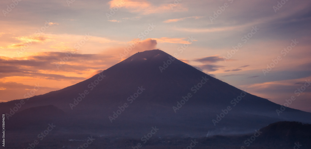 Beautiful landscape volcano mountain Agung silhouette on Bali at sunset with orange sunset sky in Indonesia