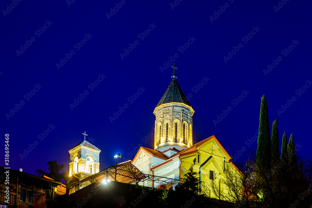 Georgia, Tbilisi all Saints Church at sunset on a winter evening. The dark blue sky. The temple is lit by lanterns Georgia, Tbilisi all Saints Church at sunset on a winter evening. The dark blue sky. The temple is lit by lanterns