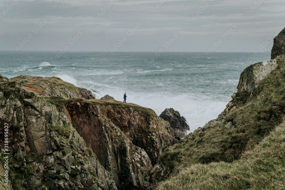 Atlantic Ocean with waves and rocks on which man is