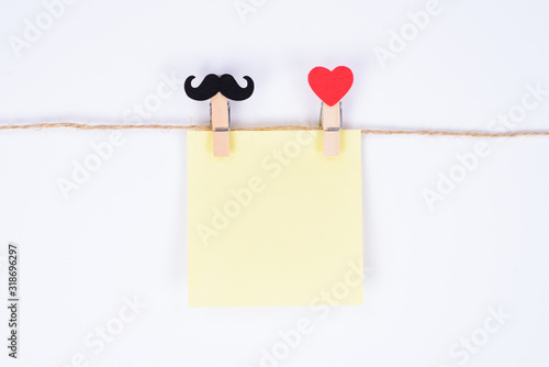 Closeup photo of two clothespins symbolizing a human pair holding sheet of paper isolated white background