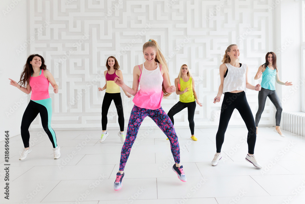 Fototapeta premium Group of happy young women in sportswear at dance fitness class in white fitness studio