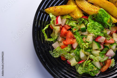 fresh vegetable salad and perfectly fireproof potato on a black plate, white background