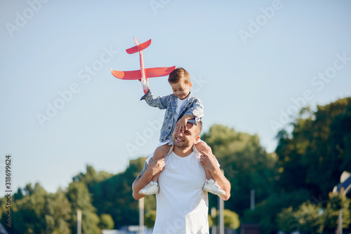 Family in a summer park. Father in a white shirt. Cute little son with an airplane