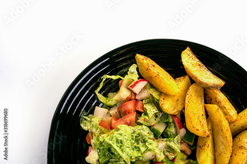 fresh vegetable salad and perfectly fireproof potato on a black plate, white background