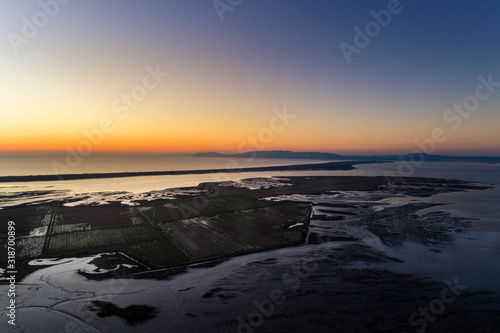Aerial view of the Sado Estuary near the village of Carrasqueira  with a rice plantation  the Troia Peninsula and the Arrabida Mountain on the background at sunset  in Portugal.