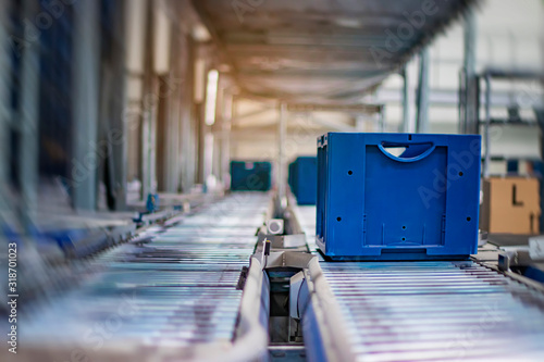 Tablou pe pânză Blue boxes in a large, fully automated logistics warehouse run on a conveyor belt