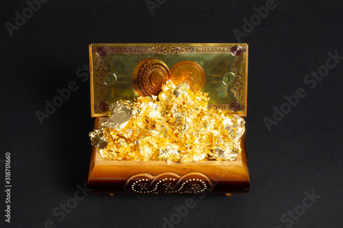 Bitcoin banknote and foil gold in the treasure trove, cryptocurrency in wooden chest, gift, decoration on black paper background.