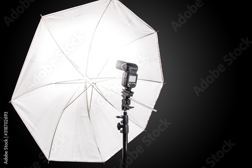 Studio stand with speedlight photo flash and white umbrella reflector photo